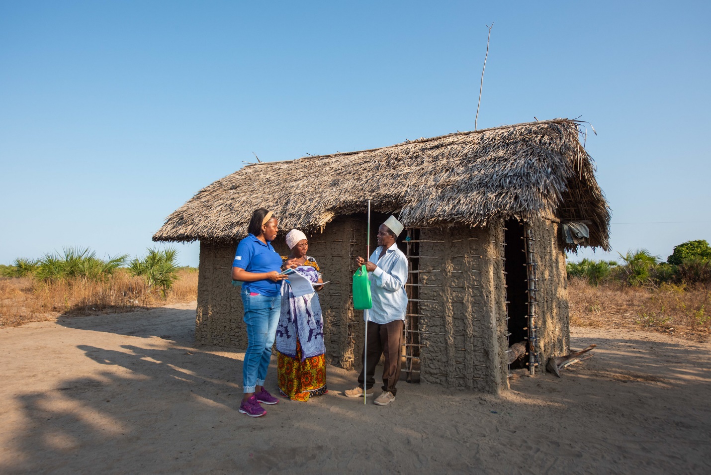 A group of people standing outside a hut  Description automatically generated with medium confidence